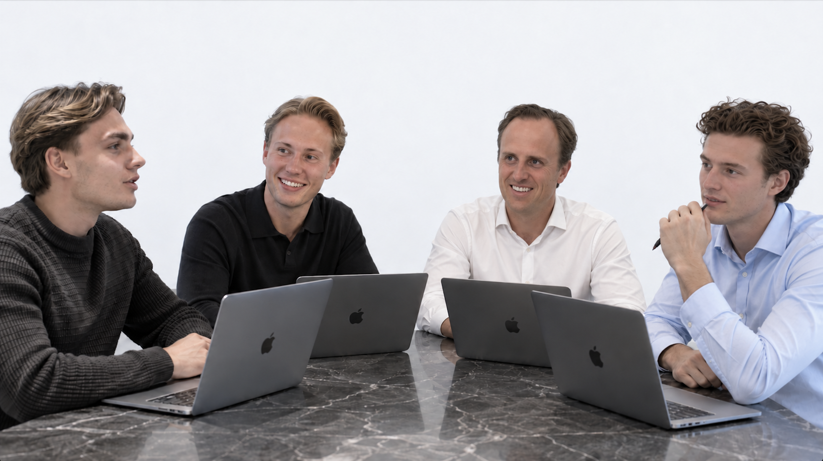 Ask Academy-teamet samlet omkring et bord med bærbare computere.