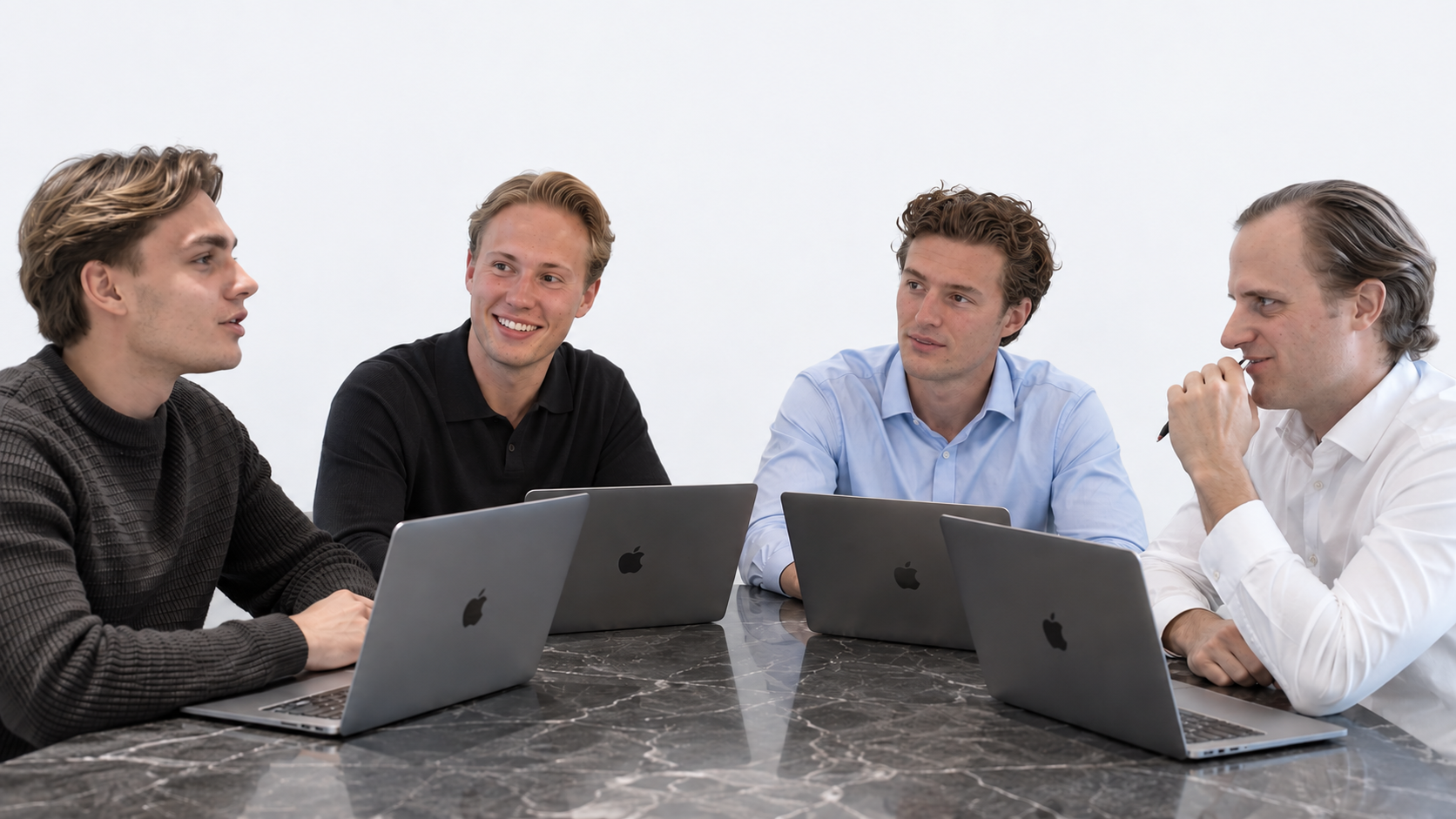 Ask Academy-teamet samlet omkring et bord med bærbare computere.